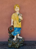 A large majolica boy holding a bouquet of flowers and a jug