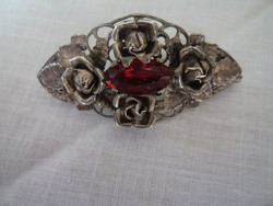 Old beautiful brooch with roses and red busy stone in the middle.
