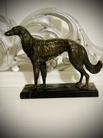 Large bronze greyhound dog sculpture on marble pedestal.