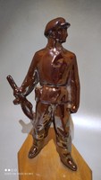 Vintage retro eosin glazed metal laborer statue on wooden sole