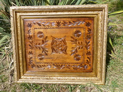 Folk wood carving in gilded picture frame.