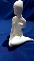 Woman sitting on white unmarked nude