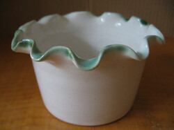 A small pot with wavy green edges