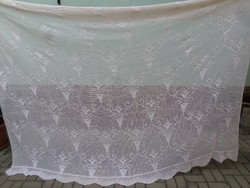 A pale cream crocheted lace curtain or bedspread with a romantic feel.