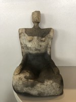A sitting figure is a small sculpture, with a naive design.