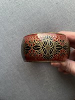 Wider style, decorative copper bracelet painted on a bright red background