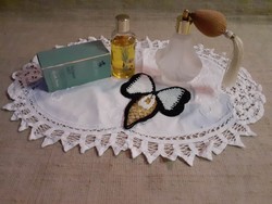 Pump perfume bottle in a Parisian branded perfume box on a small tablecloth with a pearl bow