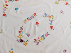 Old embroidered needlework tablecloth on colorful floral tablecloth