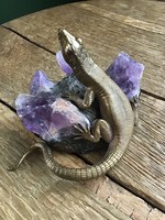 Old copper lizard statue on a bronze base decorated with amethyst mineral