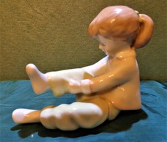 Zokni húzó kislány. Aquinkumi porcelán szobrocska / 12 cm /.
