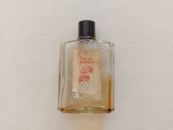 Old labeled perfume bottle with red carnation in vintage cologne bottle