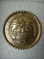 A copper wall plate with a convex ship image