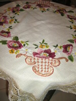 A richly hand-embroidered tablecloth with a beautiful floral lace edge