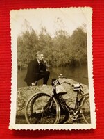 A man in an antique suit on the waterfront with a bicycle, small photo according to the pictures