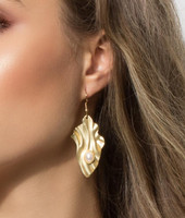 Earrings with an abstract shape, gold-colored metal with a wavy surface and an oval-shaped white glass pearl.