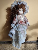 A doll with a huge porcelain head, a beautiful curly little lady with reddish brown hair in a lace hat