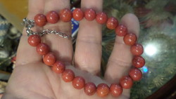 About 7-8 mm bracelet made of coral pearls, adjustable with a chain.