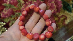 Rubber bracelet, made of larger, reddish coral beads.