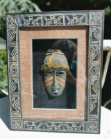 African wooden mask in a carved frame