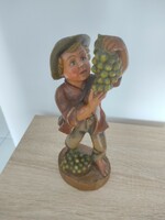 Wooden sculpture of a boy picking grapes