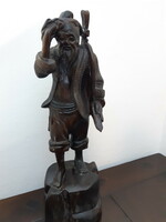 A hardwood statue depicting an Eastern sage