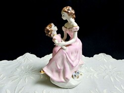 Gyönyörű porcelán hölgy, anya kislányával rózsaszín ruhában
