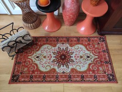 A small machine-made Persian carpet with a classic pattern in an orange tone