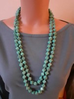 A long turquoise necklace knotted individually from cube-shaped eyes