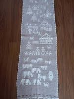 Snow-white crocheted curtain with a farm scene