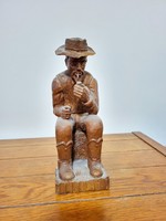 A statue of a man smoking a pipe, carved by György Sipos