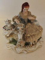 Old lacy baroque style porcelain figurine of a lady playing with a dog.
