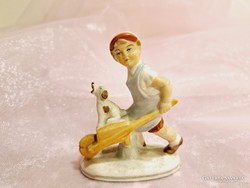 German porcelain figurine of a boy pushing a wheelbarrow with his dog.