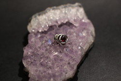 Silver charm with red stone