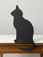 A cozy silhouette sculpture of a black cat sitting on a wooden board