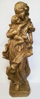 Golden Madonna with her child. Fat stone sculpture with a rustic surface