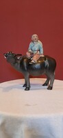 Chinese boy on the back of a buffalo with a rose in his hand. Detailed, hand-painted, 19 cm high porcelain statue.