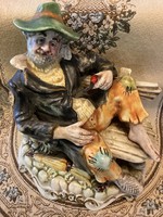 A vagabond figure resting on a porcelain bench marked Capodimonte