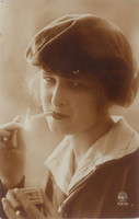 1928 – Elegant, young, French woman with a cigarette. Colored photo sheet, postcard.