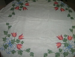 Beautiful hand embroidered bouquet of flowers with cross stitch on white needlework tablecloth