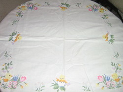Beautiful hand embroidered cross-stitch floral chick on white tablecloth