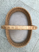 A large, beautifully shaped, oval wicker basket with a stable wooden base