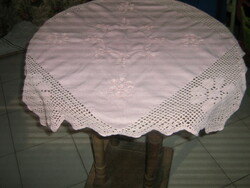 A charming hand crocheted pink tablecloth with a stitched floral edge