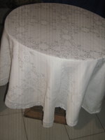 A beautiful round white silk damask tablecloth with a baroque pattern with a lace edge