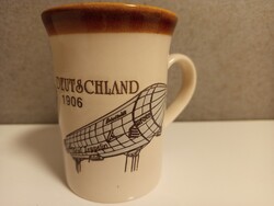 Gyönyörű, kézzel festett bögre, amely a 'Deutschland 1906' léghajót ábrázolja.