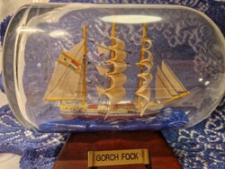 Vitorláshajó palackban, a híres német Gorch Fock gyakorló vitorlás hajó miniatűr modelljét ábrázolja