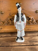 Hollóházi porcelán Népviseletben öltözött hímzett ruhás kalapos legényke.