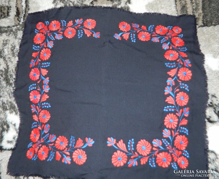 Red-blue floral embroidered tablecloth on a black background