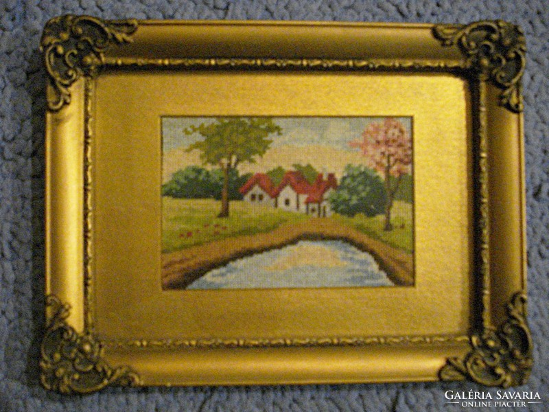 2 needle tapestries depicting a waterfront landscape in a blond frame
