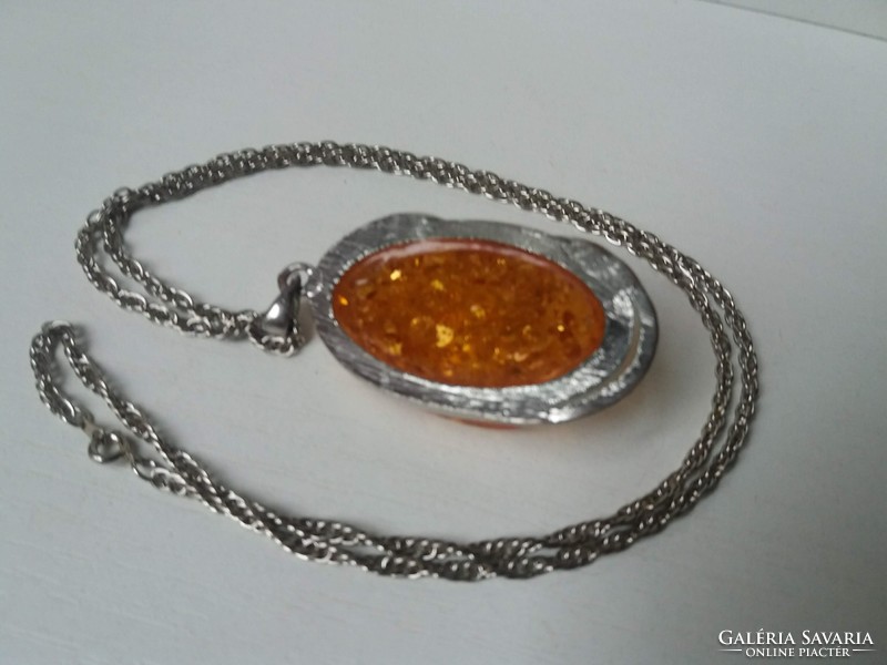 Large silver-plated pendant with an amber-colored stone on a long twisted chain