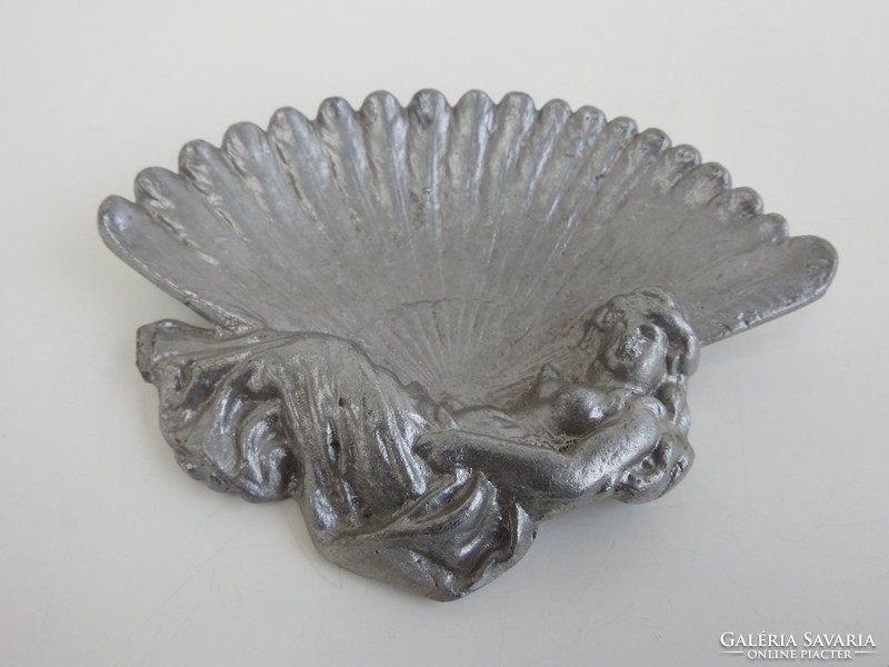 An old plastic ashtray made of aluminum in the shape of a woman with a fan
